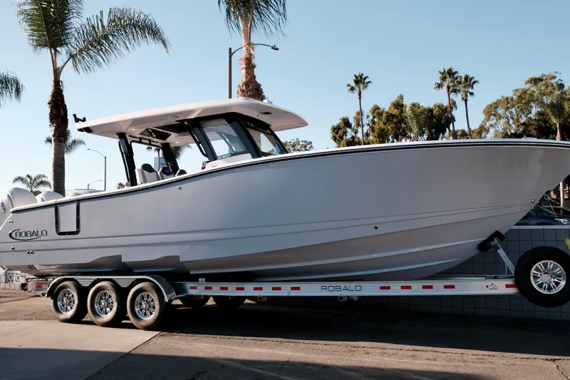 Slide: The Image of 2024 Robalo R360 Center Console boat on trailer, surrounded by palm trees. - 4