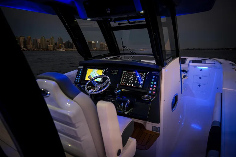 Slide: The Image of 2024 Robalo R360 Center Console boat interior with illuminated dashboard and city skyline view. - 53