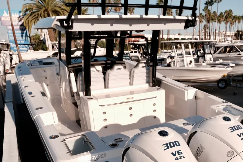 Slide: The Image of 2024 Robalo R360 Center Console boat with triple Yamaha 300 engines, docked under palm trees. - 8