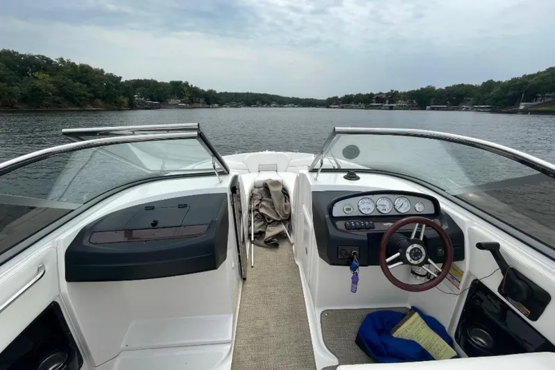 Slide: The Image of 2008 Regal 2700 Bowrider boat interior with steering wheel and dashboard on a lake. - 4
