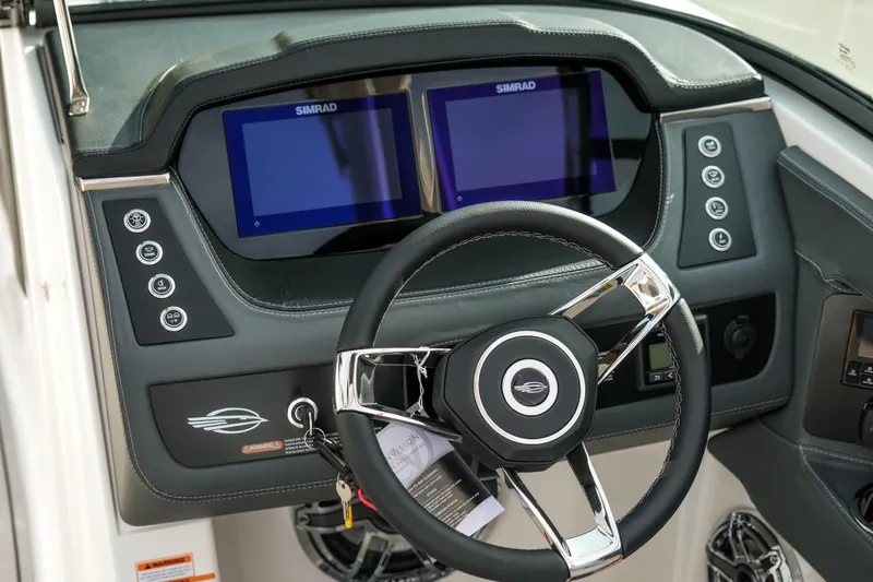 Slide: The Image of 2025 Chaparral 247 SSX boat dashboard with dual Simrad displays and sleek steering wheel. - 14