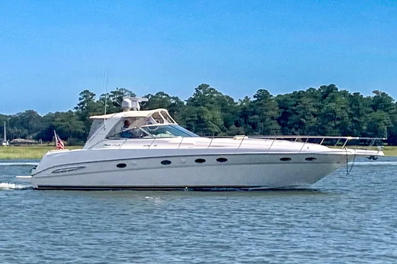 The Image of 2000 Sea Ray 460 Sundancer yacht cruising on a calm lake with forested shoreline. - 0