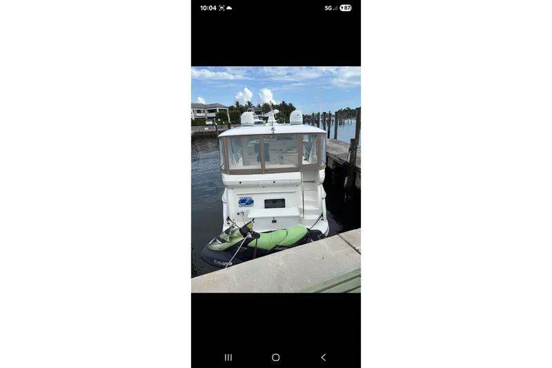Slide: The Image of 2004 Sea Ray 480 Motor Yacht docked with jet ski, clear sky background. - 3