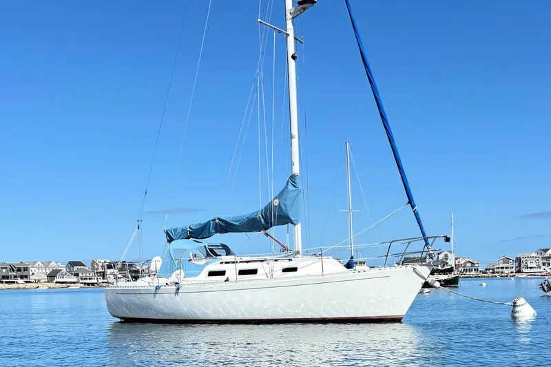 The Image of 1986 J Boats J/28 sailboat moored in a calm harbor under a clear blue sky. - 0