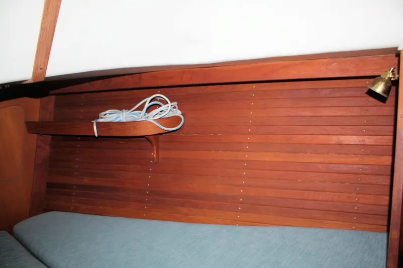 Slide: The Image of 1986 J Boats J/28 interior with wooden paneling, shelf, and blue cushion. - 25