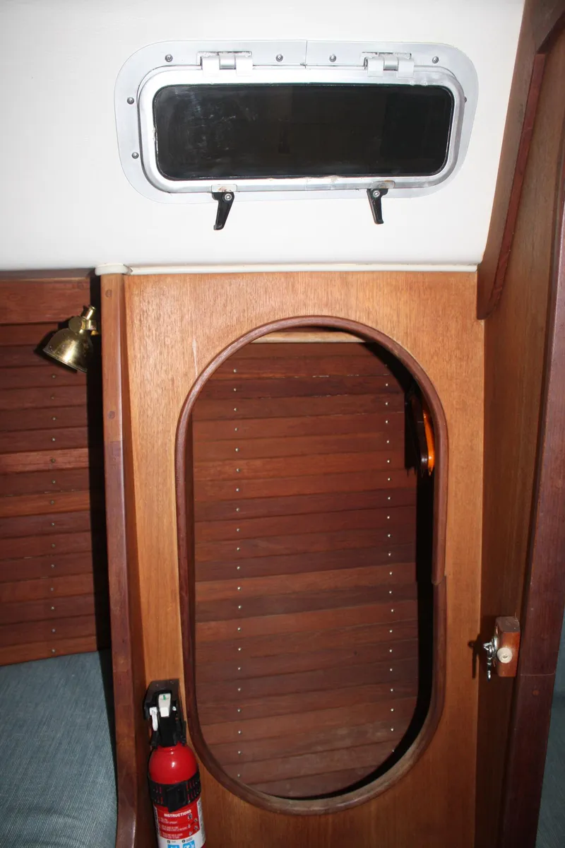 Slide: The Image of 1986 J Boats J/28 interior with wooden door, porthole, and fire extinguisher. - 28