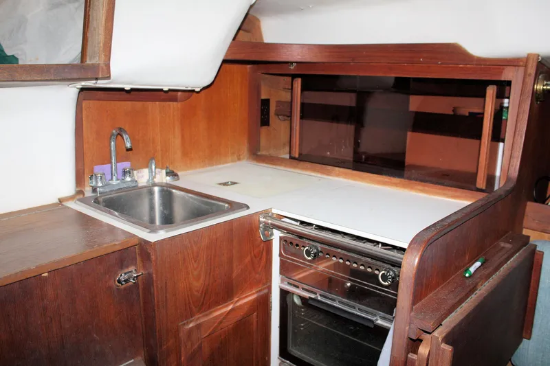 Slide: The Image of 1986 J Boats J/28 yacht interior kitchen with sink, stove, and wooden cabinetry. - 34