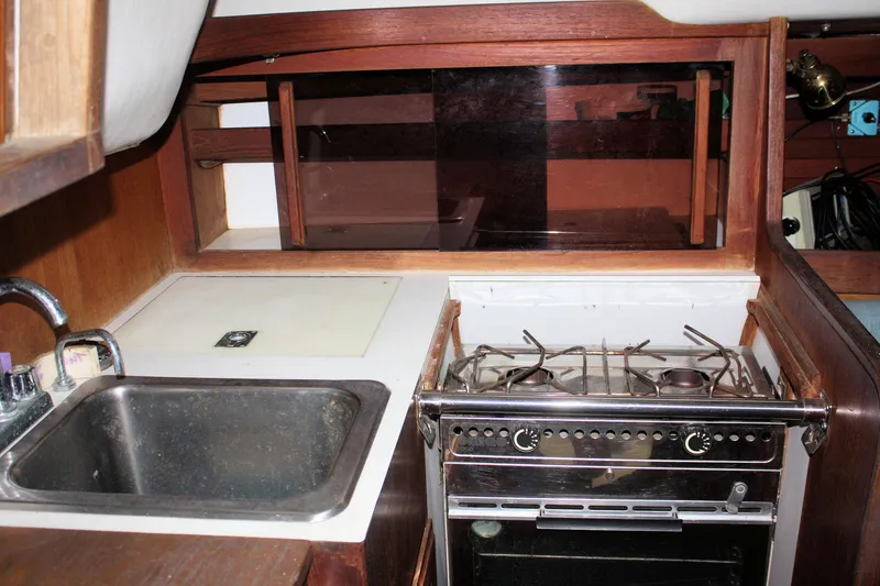 Slide: The Image of 1986 J Boats J/28 yacht kitchen with sink, stove, and wooden cabinetry. - 35