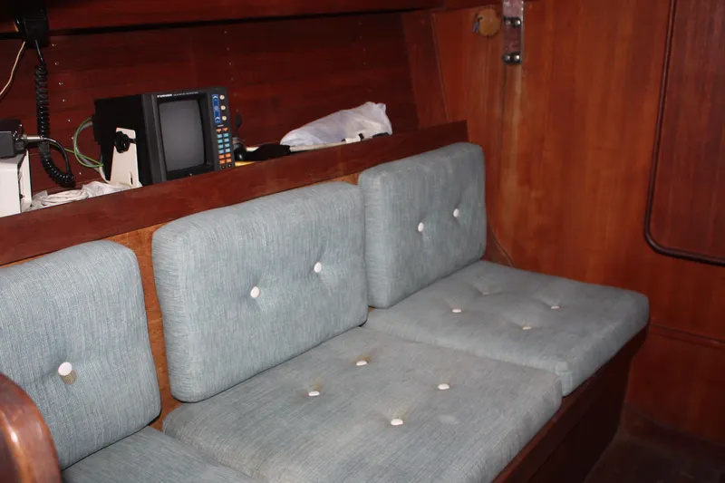 Slide: The Image of Interior of 1986 J Boats J/28 sailboat with blue cushioned seating and wooden paneling. - 36