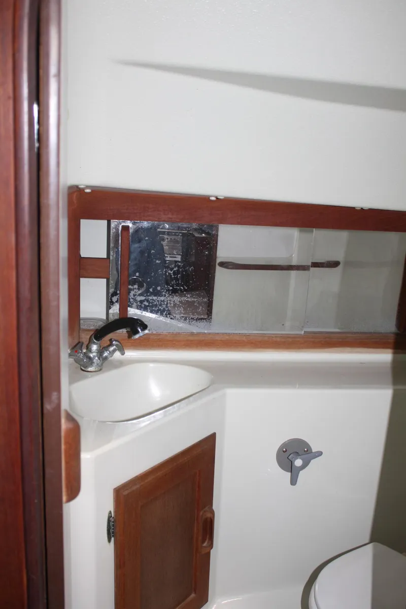 Slide: The Image of 1986 J Boats J/28 yacht bathroom with sink, mirror, and wooden cabinet. - 38