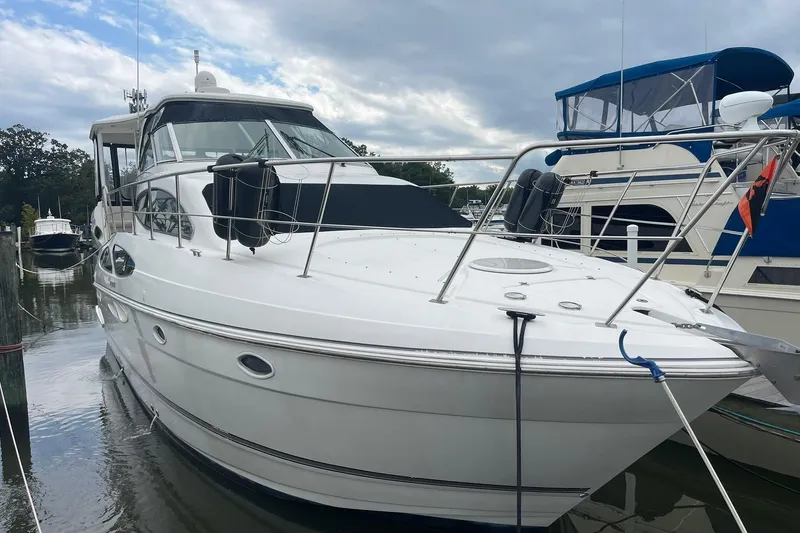 The Image of 2005 Cruisers Yachts 405 Express Motoryacht on serene water with lush green backdrop. - 0