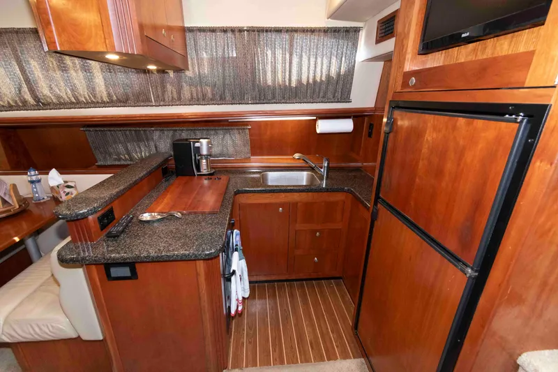 Slide: The Image of 2005 Cruisers Yachts 405 Express Motoryacht kitchen with wood cabinetry and granite countertops. - 14