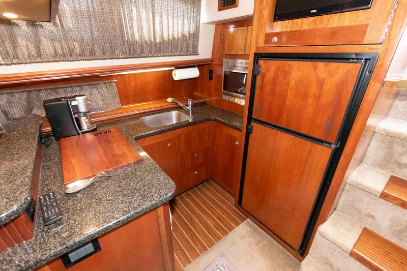 Slide: The Image of Luxurious 2005 Cruisers Yachts 405 Express Motoryacht kitchen with wood cabinetry and modern appliances. - 15