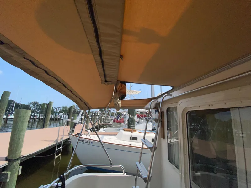 Slide: The Image of 1998 Camano Troll 31 boat docked, featuring a tan canopy and marina view. - 13