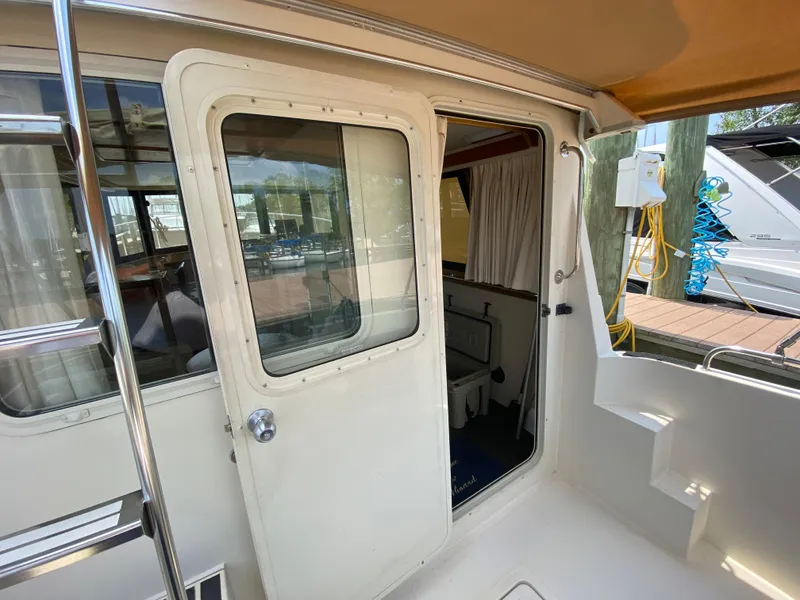 Slide: The Image of 1998 Camano Troll 31 boat interior view with open door and dockside background. - 15
