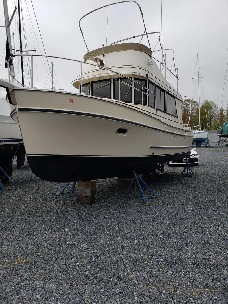 Slide: The Image of 1998 Camano Troll 31 boat on gravel, elevated on stands, with overcast sky. - 30