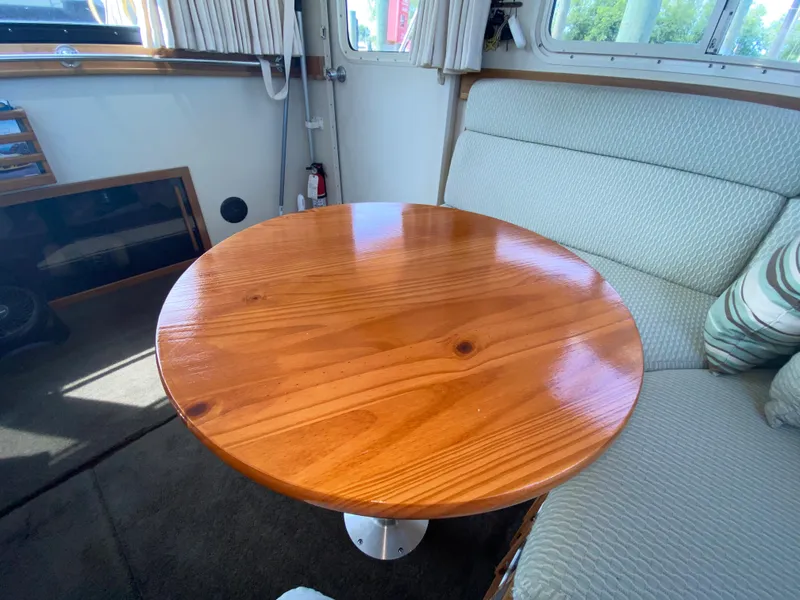 Slide: The Image of Interior of 1998 Camano Troll 31 boat with round wooden table and cushioned seating. - 32