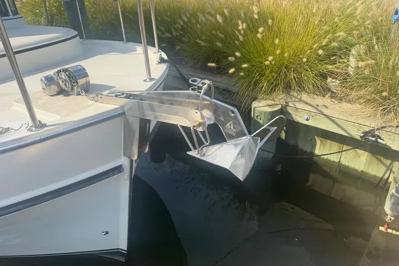 Slide: The Image of 1998 Camano Troll 31 boat with anchor, docked near grassy shoreline. - 60