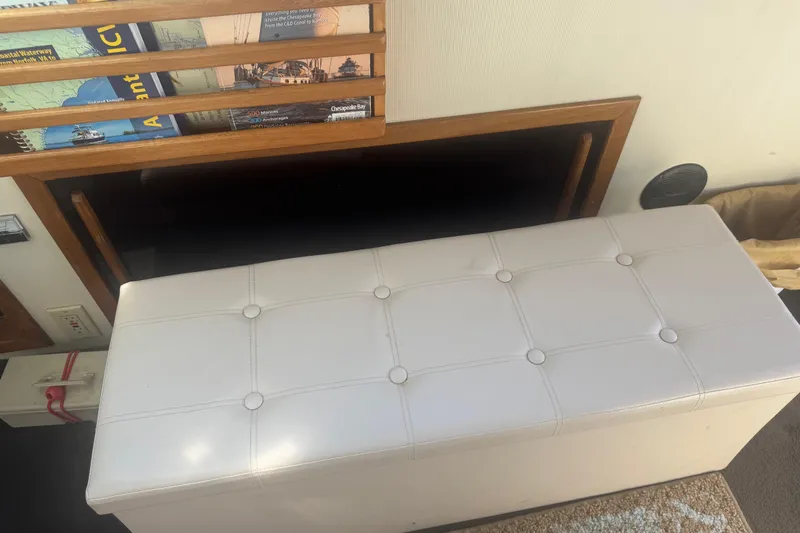 Slide: The Image of Interior of 1998 Camano Troll 31 with white cushioned bench and nautical maps. - 63