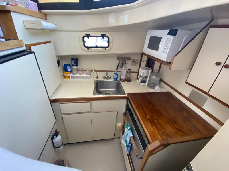 Slide: The Image of Compact kitchen in a 1998 Camano Troll 31 boat with sink, microwave, and wooden countertop. - 7