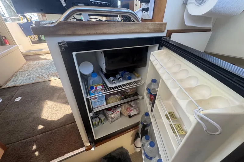 Slide: The Image of Open fridge inside 1998 Camano Troll 31 boat, stocked with drinks and food items. - 8