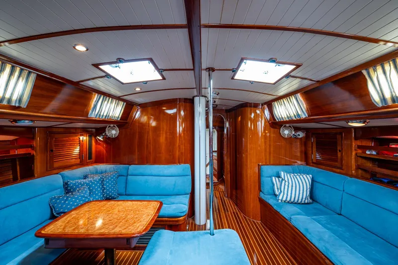 Slide: The Image of Luxurious interior of 2000 Hinckley Sou'wester Stoway Sloop with blue seating and wooden finishes. - 36