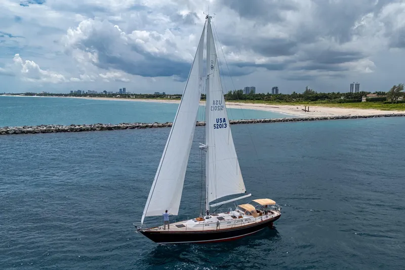 Slide: The Image of Hinckley Sou'wester Stoway Sloop 2000 sailing near a scenic coastline under cloudy skies. - 4