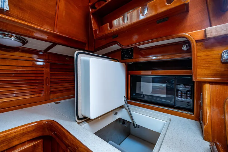 Slide: The Image of Hinckley Sou'wester Stoway Sloop 2000 yacht interior with wooden cabinetry and built-in appliances. - 40