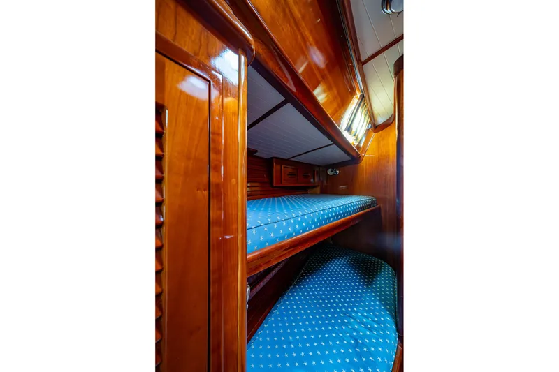 Slide: The Image of Interior of 2000 Hinckley Sou'wester Stoway Sloop with wooden bunk beds and blue cushions. - 52