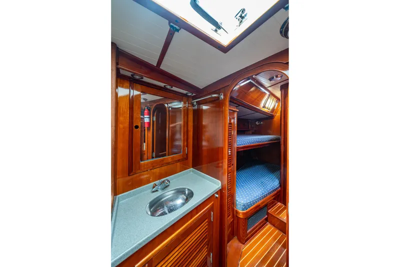 Slide: The Image of Hinckley Sou'wester Stoway Sloop 2000 interior with wooden cabinetry, sink, and bunk beds. - 57