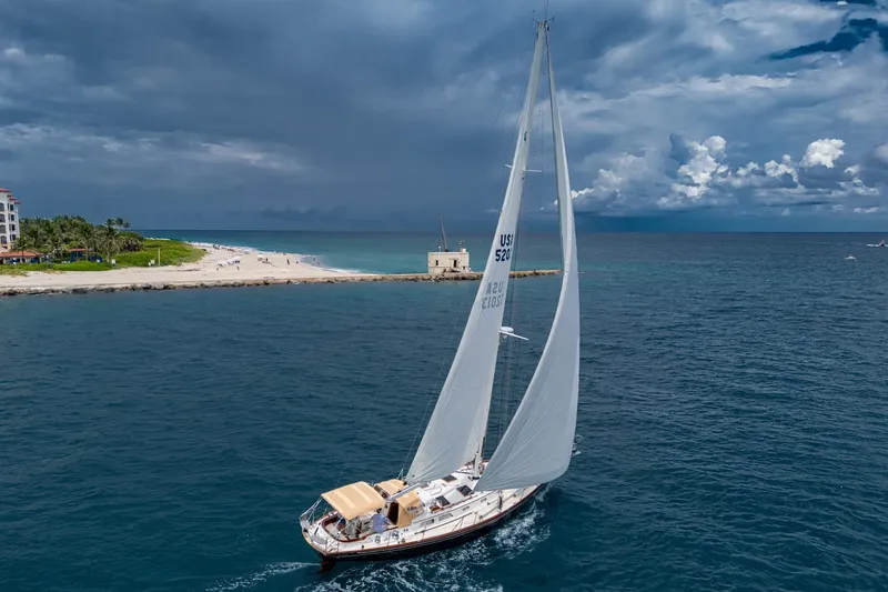 Slide: The Image of Hinckley Sou'wester Stoway Sloop sailing near a beach under a cloudy sky, 2000 model. - 7