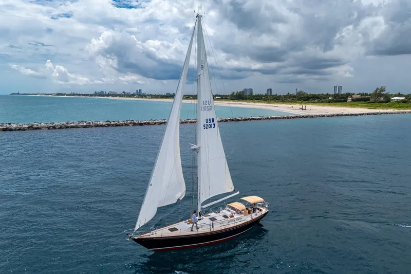 Slide: The Image of Hinckley Sou'wester Stoway Sloop 2000 sailing near a scenic coastline under cloudy skies. - 2