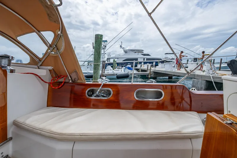 Slide: The Image of Hinckley Sou'wester Stoway Sloop 2000 interior view at marina, featuring wooden trim and seating. - 31