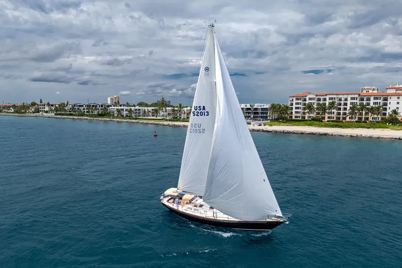 Slide: The Image of Hinckley Sou'wester Stoway Sloop sailing near coastal buildings under cloudy skies, 2000 model. - 5