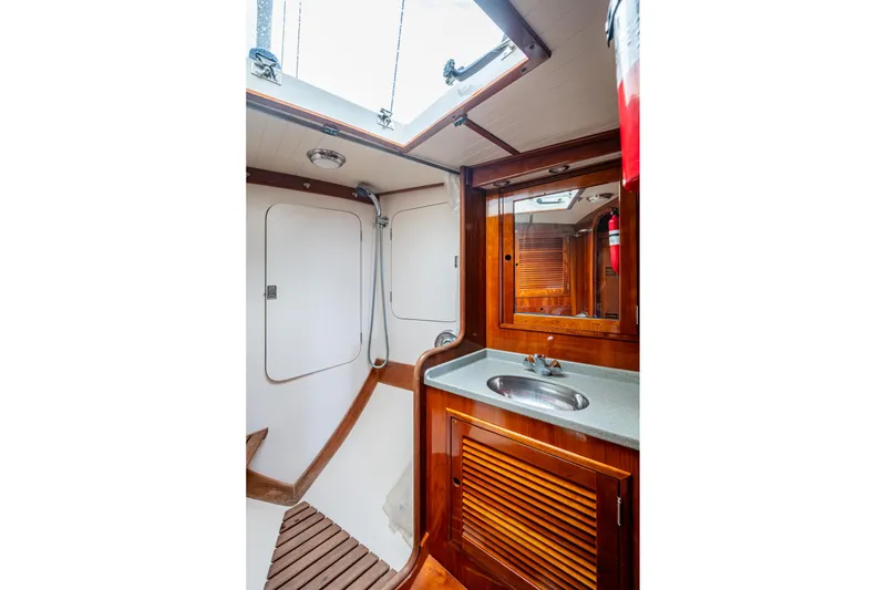 Slide: The Image of Hinckley Sou'wester Stoway Sloop 2000 yacht interior, featuring a wooden bathroom with sink and shower. - 60