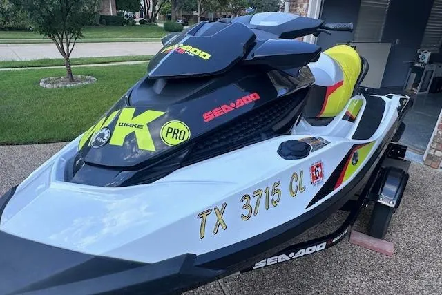 Slide: The Image of 2014 Sea-Doo Wake Pro 215 jet ski parked on driveway, featuring bold decals. - 2