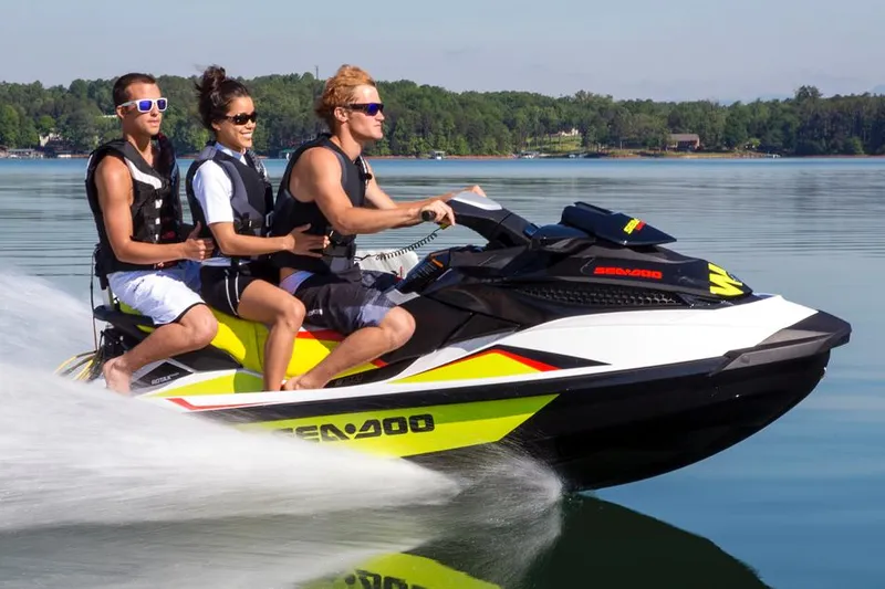 Slide: The Image of Three people riding a 2014 Sea-Doo Wake Pro 215 on a calm lake. - 22