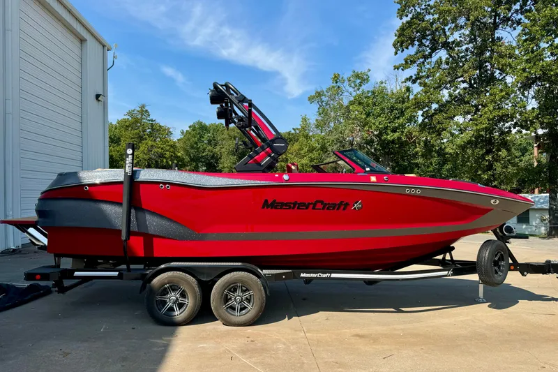 The Image of 2022 MasterCraft X24 boat in vibrant red on a trailer, parked outdoors. - 0