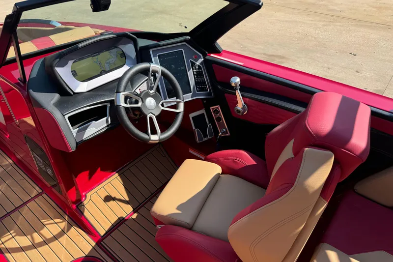 Slide: The Image of 2022 MasterCraft X24 boat interior with red and beige seating, modern dashboard, and steering wheel. - 11
