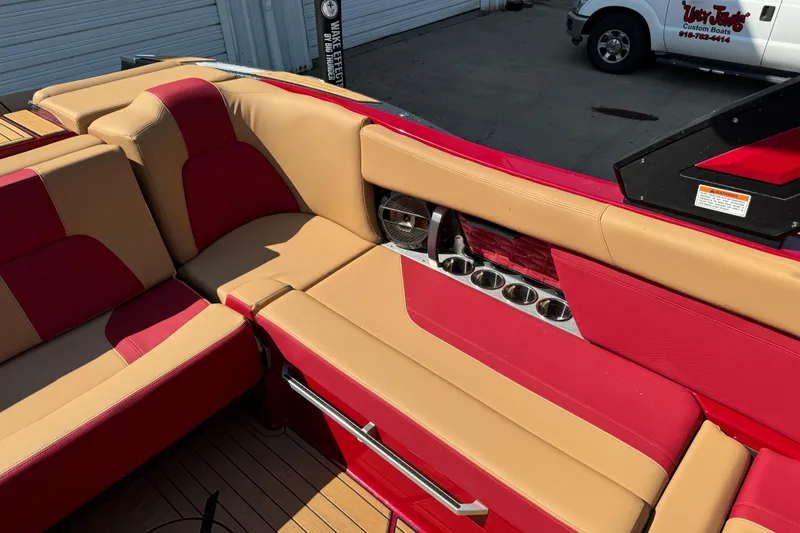 Slide: The Image of 2022 MasterCraft X24 boat interior with red and tan seating, cup holders, and sleek design. - 13