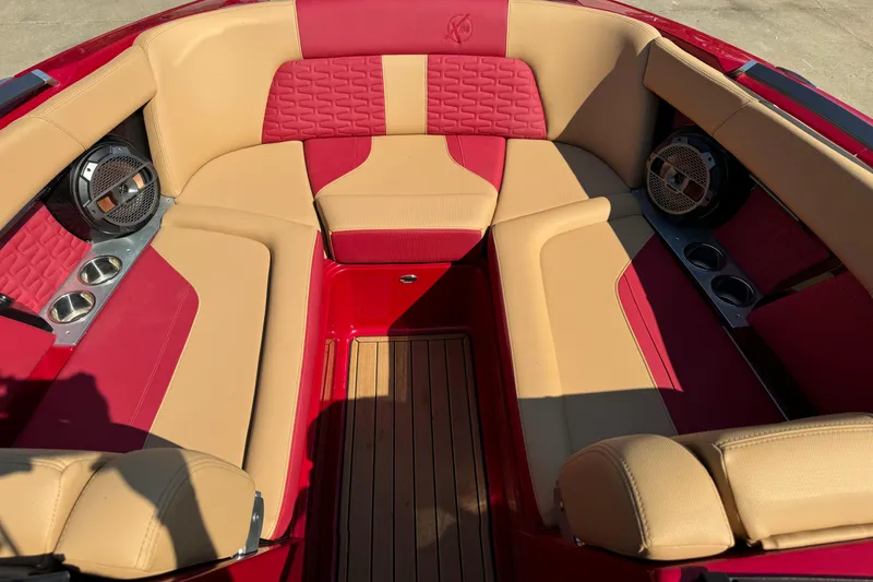 Slide: The Image of 2022 MasterCraft X24 boat interior with red and beige seating, cup holders, and speakers. - 16