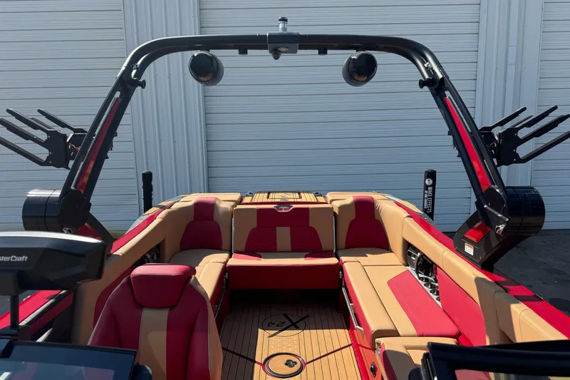 Slide: The Image of 2022 MasterCraft X24 boat interior with red and tan seating, wakeboard racks, and speakers. - 18