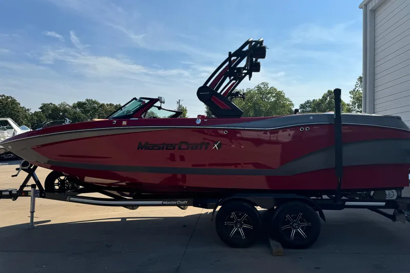 Slide: The Image of 2022 MasterCraft X24 boat in red on a trailer, parked outdoors. - 4