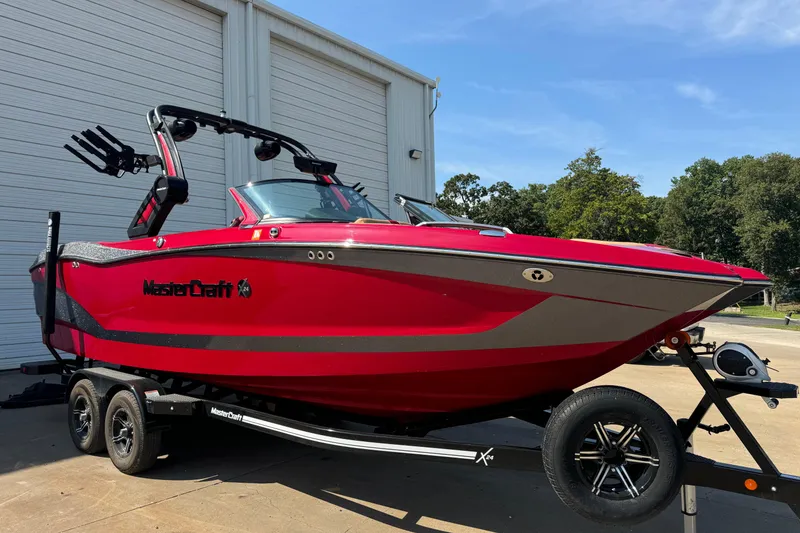 Slide: The Image of 2022 MasterCraft X24 boat in vibrant red on a trailer, parked outdoors. - 7