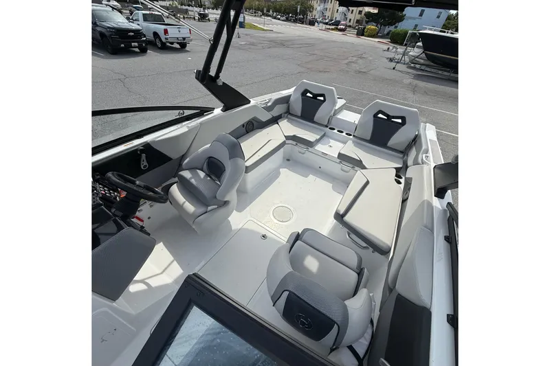 Slide: The Image of 2025 Scarab 235SE boat interior with modern seating and steering wheel, parked in a lot. - 10