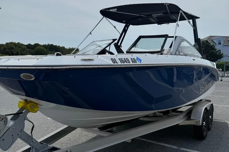 Slide: The Image of 2025 Scarab 235SE boat on trailer, blue and white design, parked outdoors. - 4