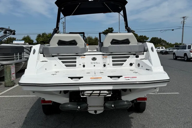 Slide: The Image of 2025 Scarab 235SE boat rear view in a parking lot, showcasing sleek design and seating. - 7