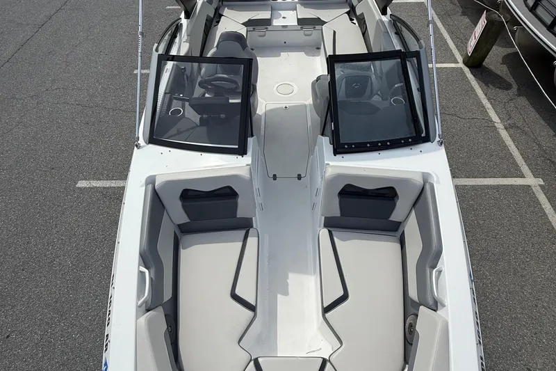 Slide: The Image of 2025 Scarab 235SE boat interior with sleek seating and dual windshields, parked on asphalt. - 9