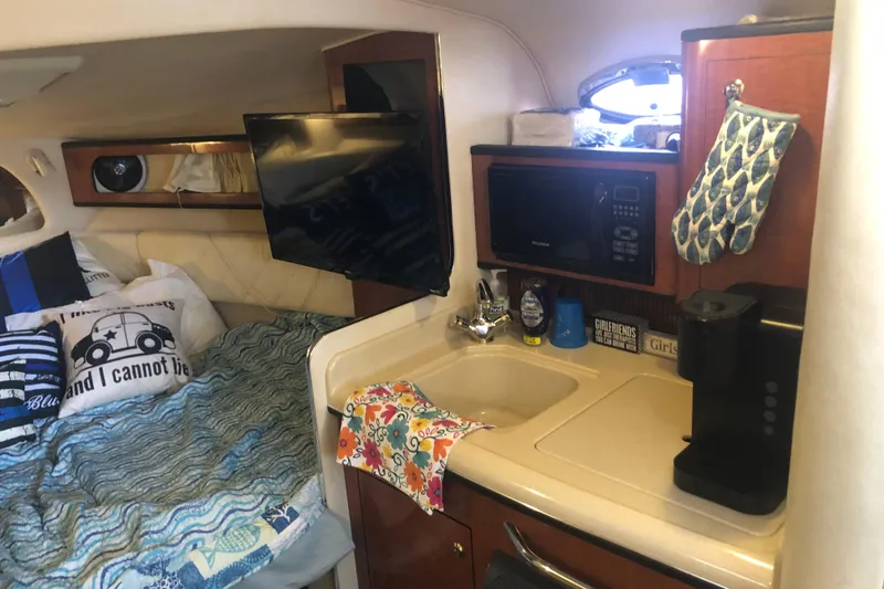 Slide: The Image of Interior of a 2004 Sea Ray 280 Sundancer with cozy bed, kitchenette, and TV. - 15