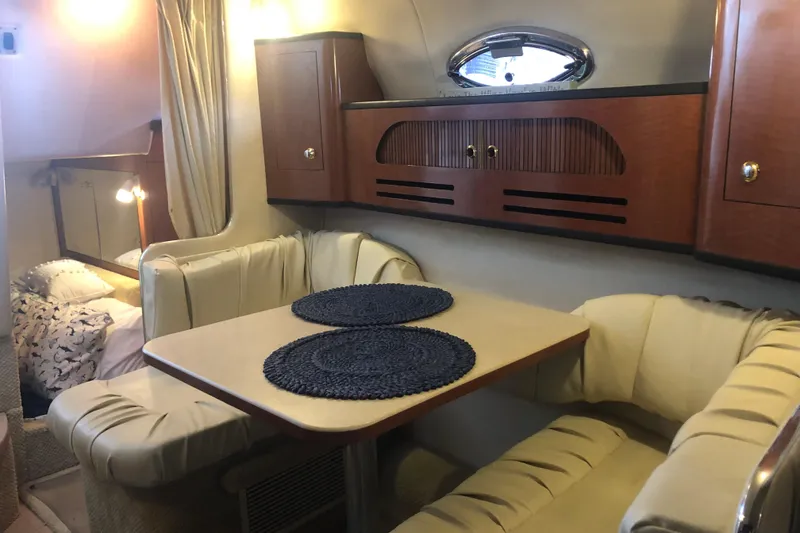 Slide: The Image of 2004 Sea Ray 280 Sundancer cabin interior with dining area and cozy seating. - 17
